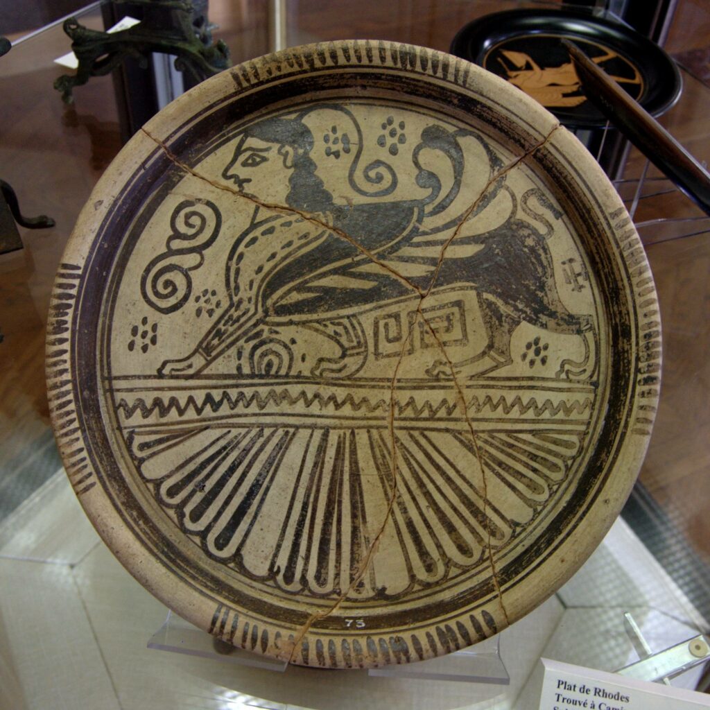 Rhodian plate featuring a Sphinx design, dating back to the end of the 7th century BC. Discovered in Kameiros, Rhodes, this ancient artifact showcases intricate East Greek pottery artistry with symbolic motifs. Photo credit: User Bibi Saint-Pol, Wikimedia Commons, 2007.